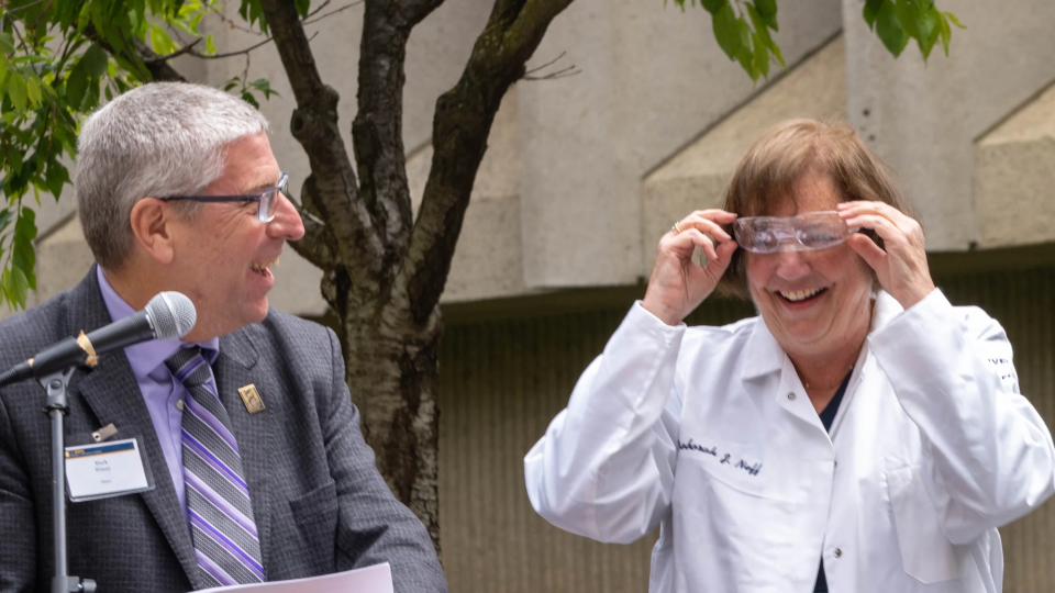 Deb Neff adjusts her safety glasses, after receiving them and a personalized lab coat from Dean Winey, left, Chancellor May and Professor McAllister, during a University Foundation Board luncheon outside Green Hall.